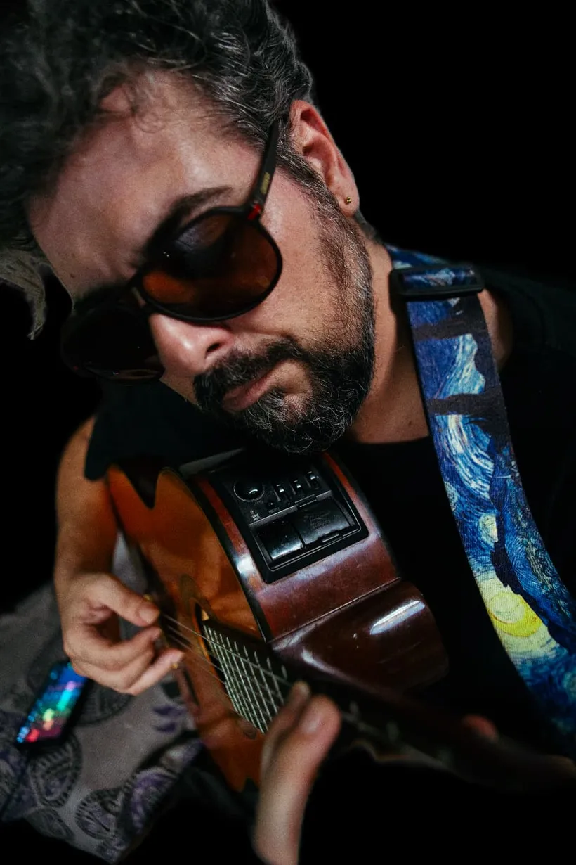 Faba con su guitarra, en penumbra cálida